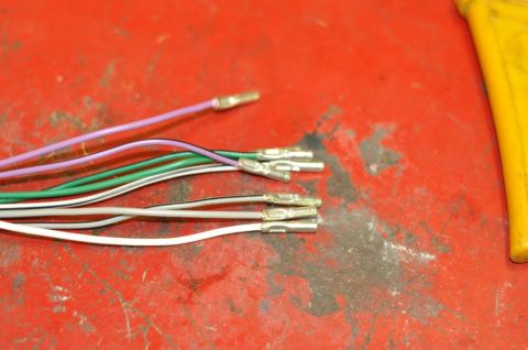 1996 Ford Bronco - A collection of electrical wires, some with crimped connectors, lies on a textured red surface next to a yellow object.