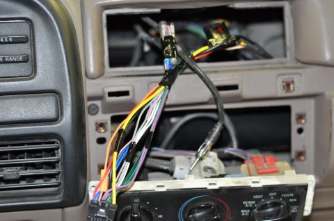 1996 Ford Bronco - Exposed wiring and climate controls are visible in the dashboard of a vehicle.