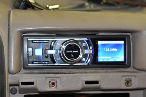 1996 Ford Bronco - Close-up of an aftermarket car stereo installed in a dashboard, displaying radio frequency and time.
