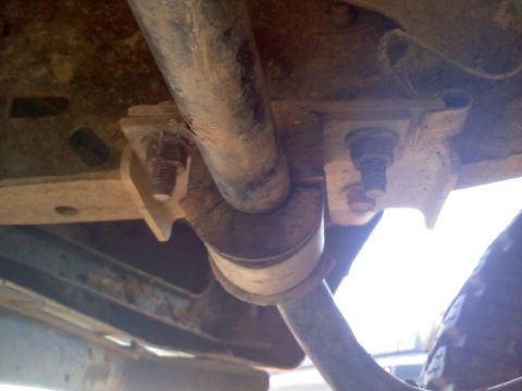 1990 Ford Bronco - Underside view of rusty suspension components, including bolts and a pipe, with a Supermotors.net watermark.