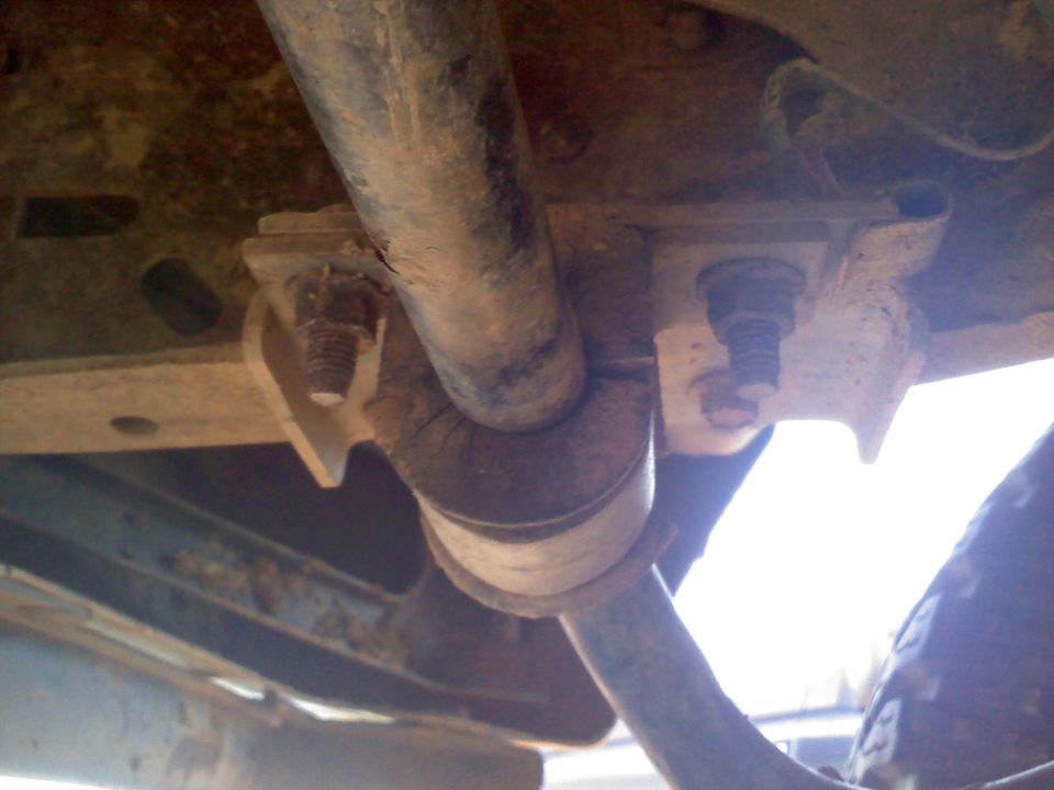 Close-up of rusty suspension parts with bolts and a pipe