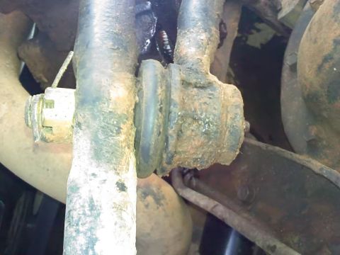 1990 Ford Bronco - This image shows a close-up view of heavily corroded vehicle suspension components, including a rubber bushing and metal linkages.