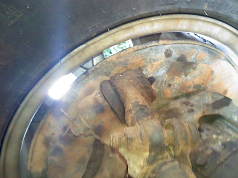 1990 Ford Bronco - Close-up view of heavily rusted suspension components and a tire, with some text visible on the tire sidewall.