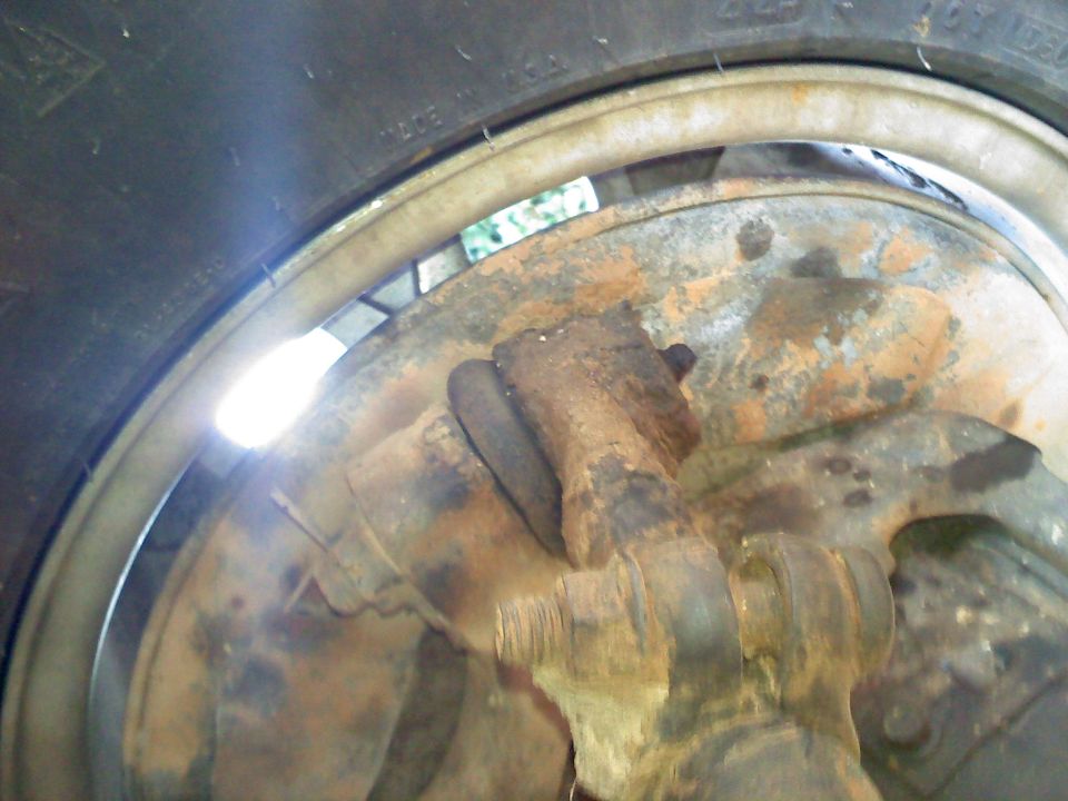 Close-up of rusty suspension parts and a tire with visible text