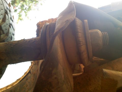 1990 Ford Bronco - Close-up of a rusted suspension part, likely from an older vehicle, with a tire in the background.