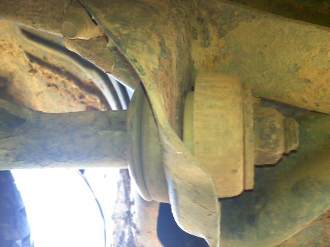 1990 Ford Bronco - This image shows a close-up view of a worn suspension bushing and bolt, part of a vehicle's undercarriage.
