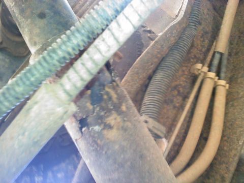 1990 Ford Bronco - This close-up shows the underside of a vehicle with various hoses and rusted components.