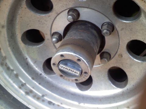 1990 Ford Bronco - A Warn locking hub is visible on a silver wheel, indicating a part of a vehicle's drivetrain.