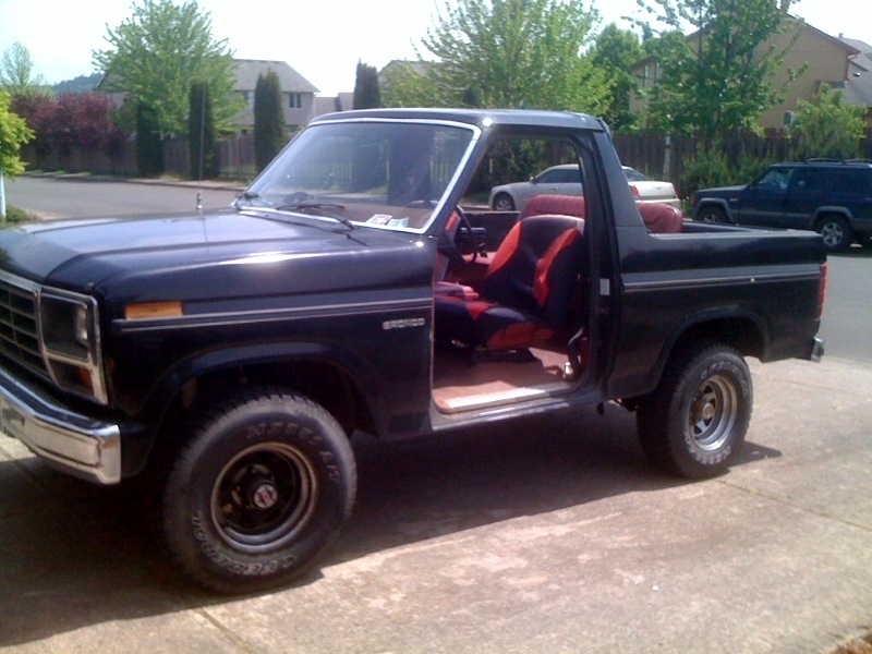 Black 1985 Ford Bronco, 3/4 front view, red and black interior