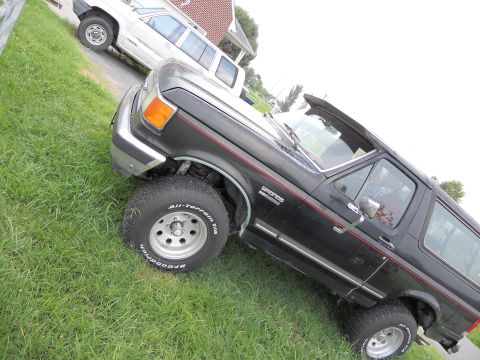 1988 Ford Bronco - A 1988 Ford Bronco is parked on a grassy incline next to another vehicle.