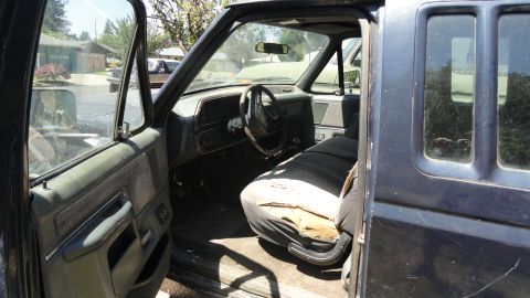 1989 Ford Bronco - Interior view of a 1989 Ford Bronco, showing the worn driver's seat and dashboard.