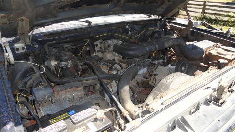 1989 Ford Bronco - The engine bay of a vehicle, showing various components including the battery and fan.