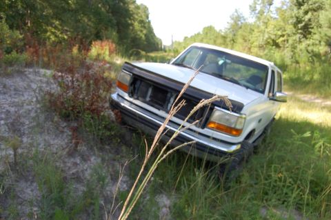 1994 Ford Bronco - This SUV appears to be stuck in the grass off a dirt road, with its hood open and grille removed.