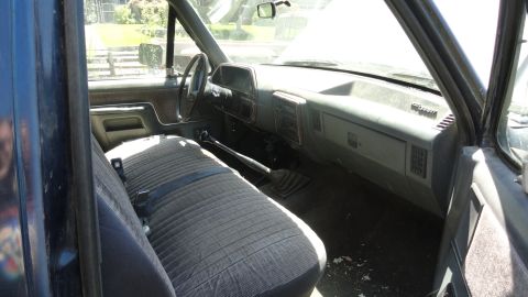 1989 Ford Bronco - Interior view of a truck with a bench seat and dashboard, showing the floor shifter and an open hood.