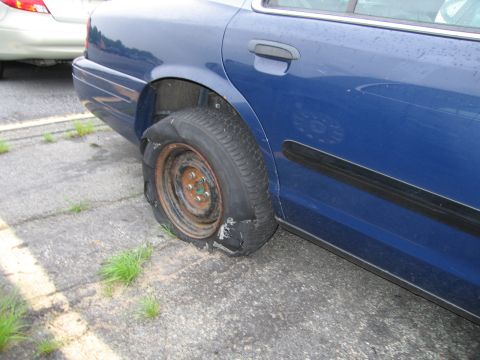 2001 Ford Crown Victoria - A blue 2001 Ford Crown Victoria is parked with a severely damaged rear tire.