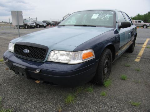 2001 Ford Crown Victoria - A 2001 Ford Crown Victoria with a two-tone paint job sits in an outdoor lot.