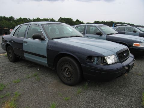 2001 Ford Crown Victoria - Two-tone Ford Crown Victoria parked in a lot with other similar vehicles.