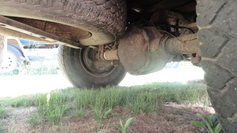 1989 Ford Bronco - Close-up of the undercarriage of a vehicle, showing the rear axle and a spare tire.