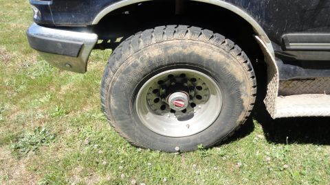 1989 Ford Bronco - Close-up of the front wheel and fender of a 1989 Ford Bronco, showing the tire and chrome bumper detail.