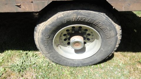 1989 Ford Bronco - A close-up view of a Firehawk tire mounted on a heavy-duty truck wheel, with part of a wooden structure visible above.