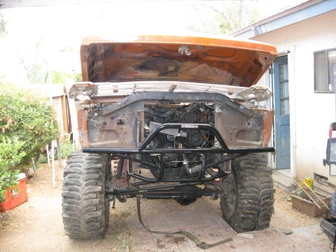 1969 Ford F-250 - Front view of an orange truck with its hood up, revealing the engine bay and heavy-duty off-road tires.