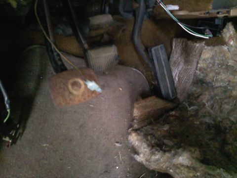 1990 Ford Bronco - The interior floor of a vehicle shows the brake and gas pedals, with visible wear and tear on the carpet and surrounding components.