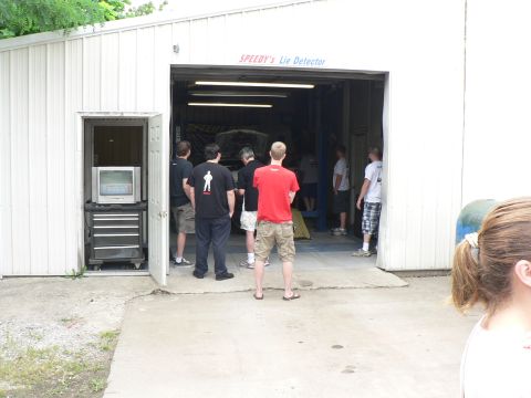 2004 Mercury Marauder - A group of people stand around a car inside a garage, with a sign above the entrance reading "SPEEDY's Lie Detector".