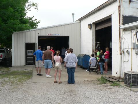 2004 Mercury Marauder - People are gathered outside a garage, with some looking inside the open bay door.
