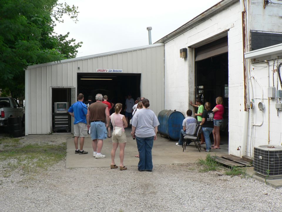 group of people standing around a garage with the door open, some inside