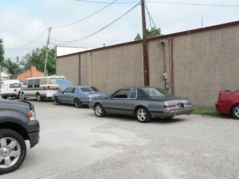 2004 Mercury Marauder - Several vehicles are parked in a lot, including a gray coupe and a blue coupe with its hood open.