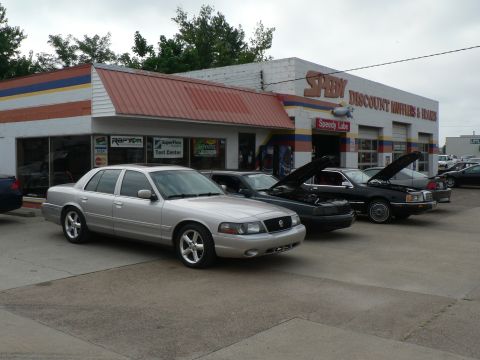 2004 Mercury Marauder - A silver sedan is parked in front of a Speedy Discount Mufflers & Brakes shop, with several other vehicles visible.