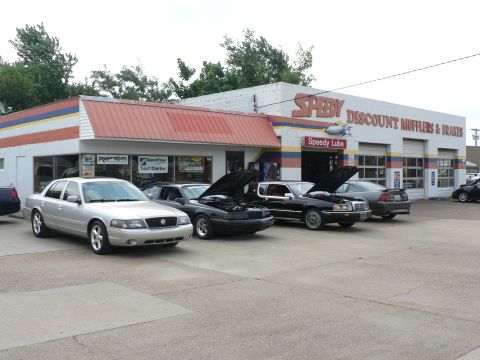 2004 Mercury Marauder - Several cars are parked outside a repair shop, with some hoods open, suggesting service work.