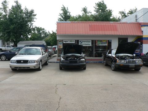 2004 Mercury Marauder - A silver 2004 Mercury Marauder is parked in front of a shop with its hood open, alongside two other vehicles.