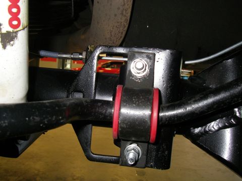 1990 Ford Bronco - Close-up of an aftermarket sway bar end link with red bushings.