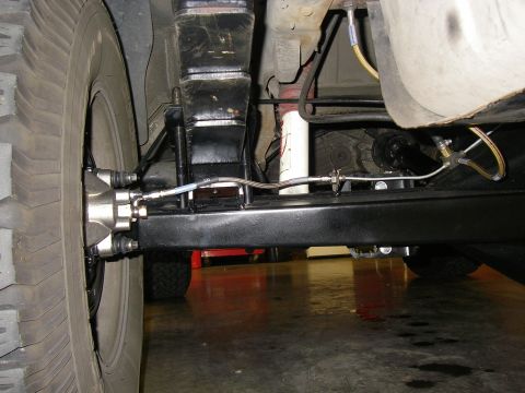 1990 Ford Bronco - Close-up of the undercarriage shows the rear axle assembly and brake system of an unidentified vehicle.