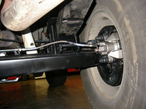 1990 Ford Bronco - Close-up view of the rear axle assembly, showing the brake caliper and suspension leaf spring.