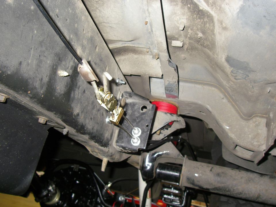 Underside view of a vehicle's suspension with red polyurethane bushings and metal brackets