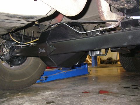 1990 Ford Bronco - Under-vehicle view of a black-painted Currie fabricated 9-inch rear axle installed under a leaf-sprung frame, with the raised CURRIE logo o…