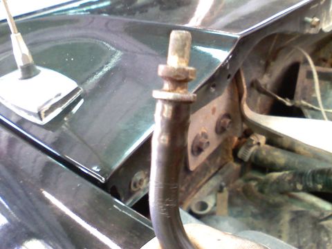 1990 Ford Bronco - Close-up of a rusty metal pipe and antenna base on a black car hood.