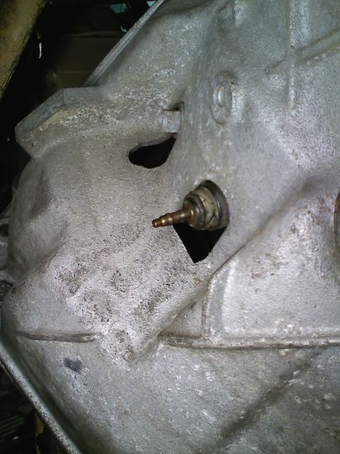 1990 Ford Bronco - Close-up view of a transmission housing a brass fitting.