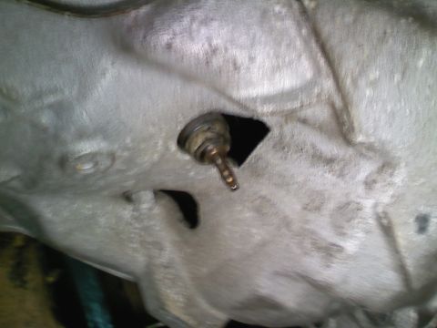 1990 Ford Bronco - A close-up view of a vehicle's transmission housing shows a sensor or plug protruding from the casing.
