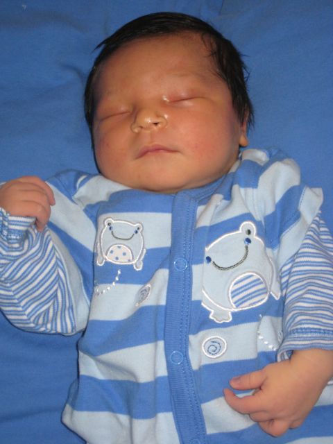 2008 Ford F-250 - A newborn baby sleeps peacefully on a blue surface, dressed in striped pajamas adorned with frog illustrations.