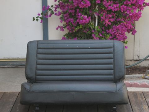 1986 Ford Bronco - This black vinyl bench seat features horizontal pleating and appears to be a replacement part for an older vehicle.