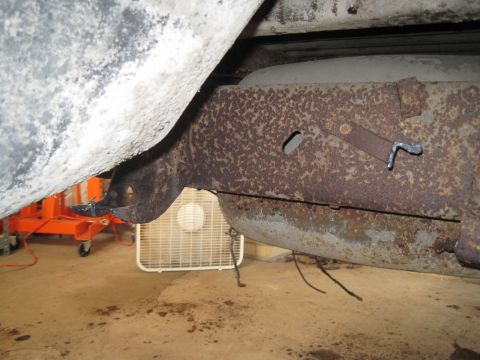 1979 Ford Bronco - Close-up view of heavily corroded vehicle frame and suspension components, with a white fan visible in the background.