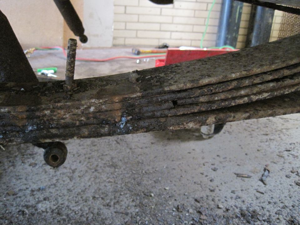 Close-up of a rusty leaf spring assembly with a bolt protruding