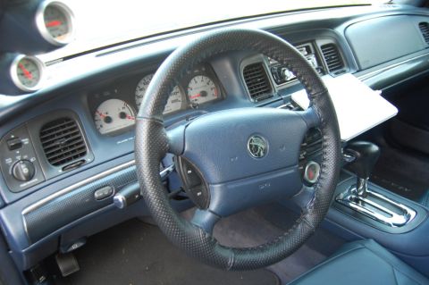 1985 Mercury Grand Marquis - The interior of a 1996 Mercury Grand Marquis, a blue dashboard, leather-wrapped steering wheel, and prominent gauges.