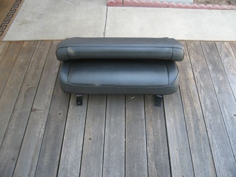 1986 Ford Bronco - Two black leather seats are shown stacked on a weathered wooden deck.