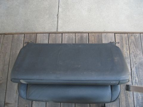 1986 Ford Bronco - A black car seat cushion is shown from above, placed on a wooden deck.