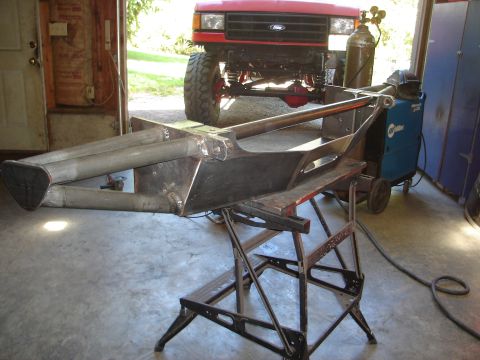 1989 Ford Bronco - A custom bumper is being fabricated in a garage, with a red Ford Bronco visible in the background.
