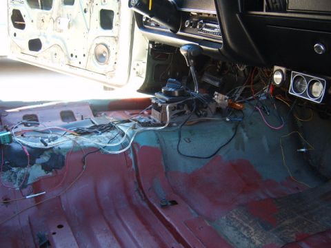 1973 Ford Ranchero - Interior of a car undergoing restoration, with wiring and floor pan exposed.